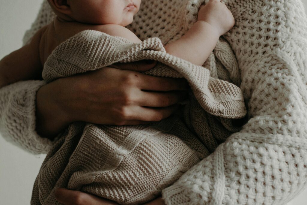 A tender moment of a mother holding her baby wrapped in a blanket, exuding warmth and care.